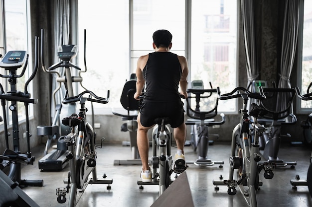 Photo a man is riding a bike in front of a window with the words gym on the wall