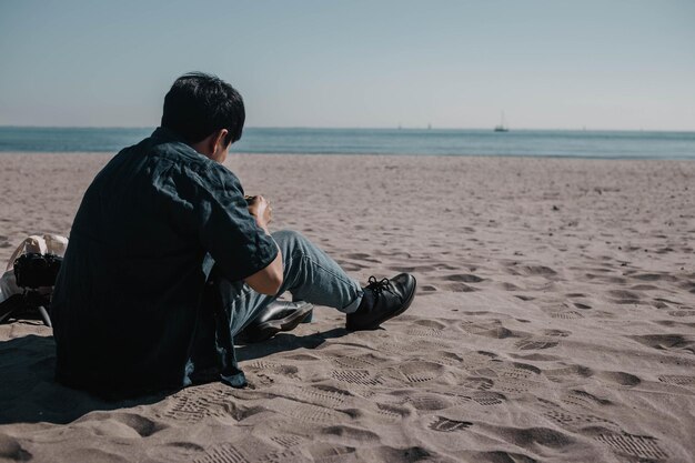 Un uomo è seduto sulla spiaggia