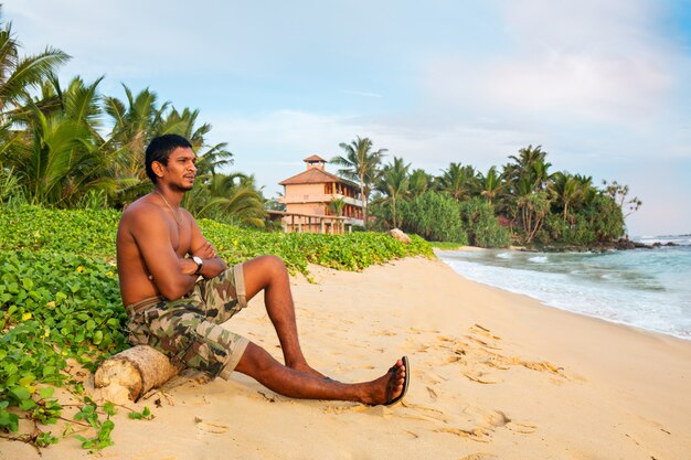 A man is sitting by the ocean