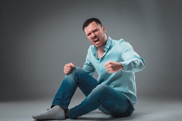 The man is sitting on the floor isolated on gray background man showing different emotions