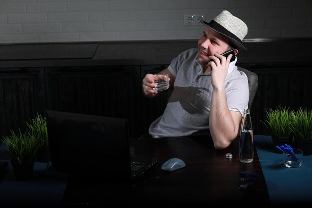 Man is sitting at his desk and working on a laptop