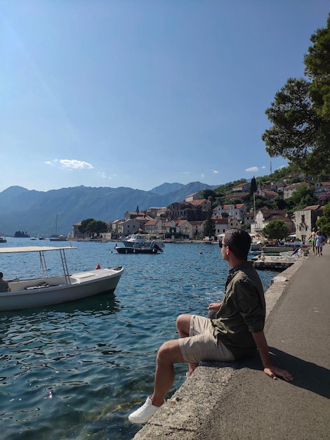 남자는 Perast Montenegro의 구시가지에 앉아서 도시 경관을 바라보고 있다