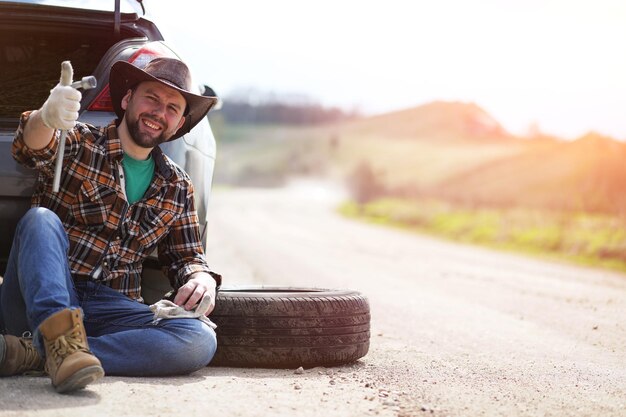 Photo man is sitting on the road by the car