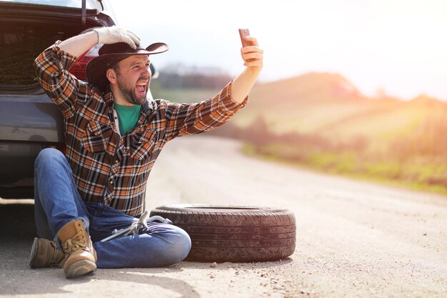 Man is sitting on the road by the car