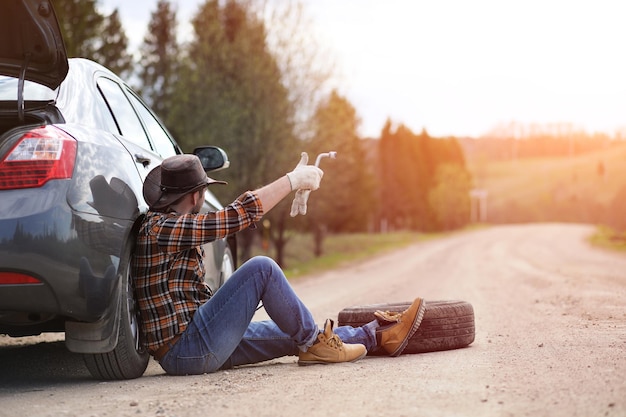 Man is sitting on the road by the car