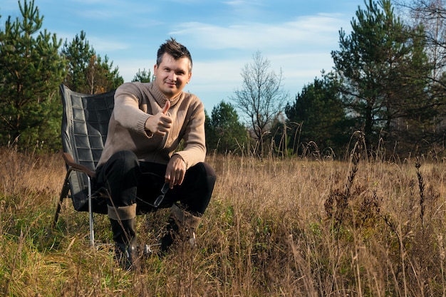 A man is sitting in a rocking chair in nature.