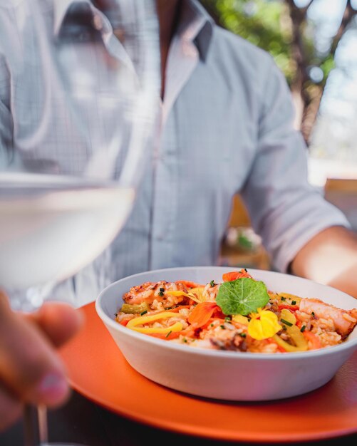 男性が食べ物の入ったボウルとコップ一杯の水を持つテーブルに座っています。