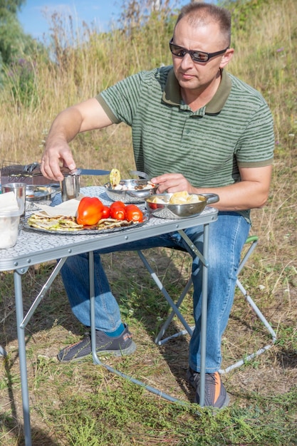 A man is sitting at a table with a table that has food on it.