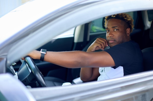 Man is sitting behind the wheel in the car with his hand on the steering wheel