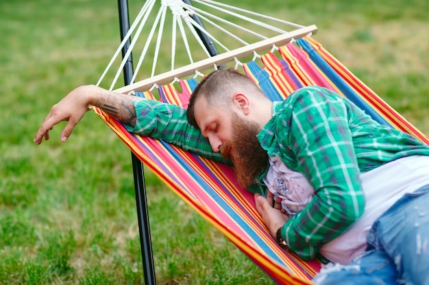 The man is sleeping on a hammock