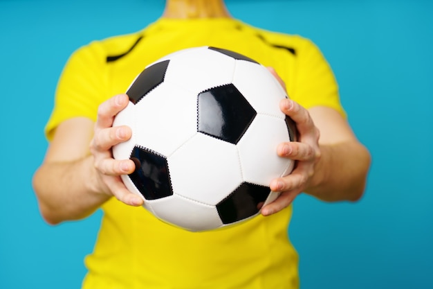 Man is socccer fan in yellow t-shirt with soccer ball on blue background