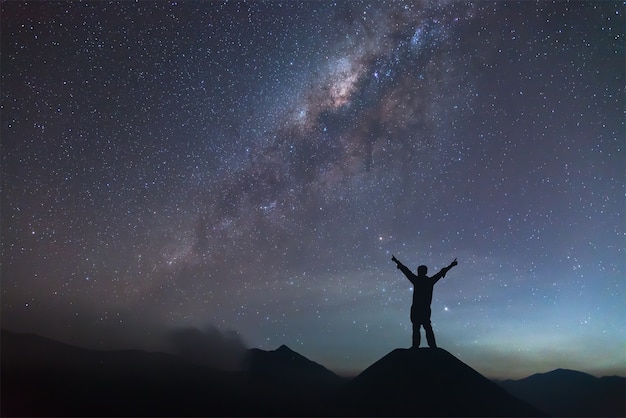 Man is spreading hand on hill and seeing the Milky Way