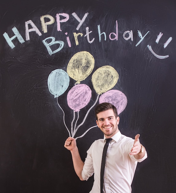 Man is standing against drawing balloon and happy birthday.