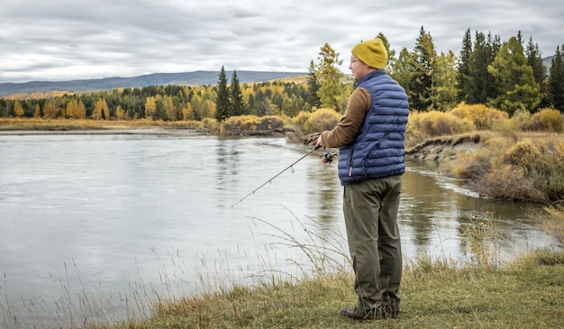 Premium Photo  A fisherman is fishing by spinning on the river bank  standing on a wooden platform