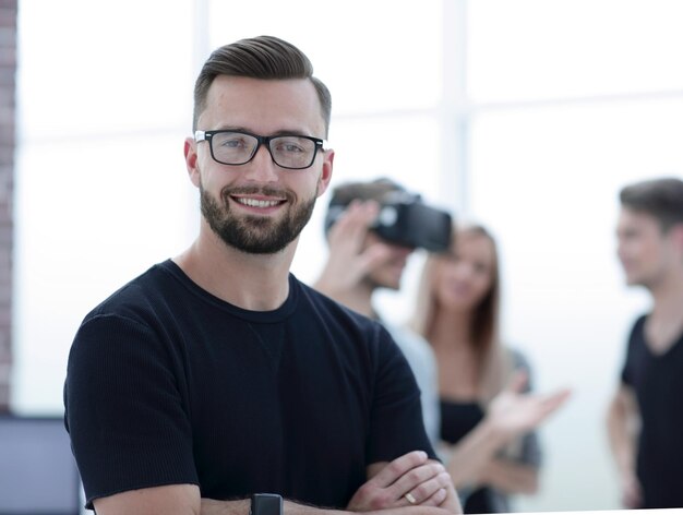 A man is standing with his hands crossed young entrepreneurs are testing a new game in the background