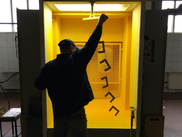 A man is standing in a yellow room with a light on the wall that says " the word " on it ".