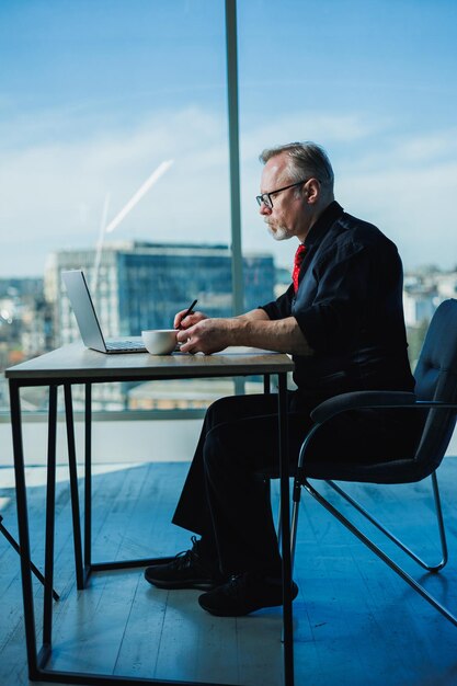 Photo the man is a stylish freelancer a grayhaired businessman on a workplace in the office adult bearded boss in the office