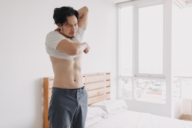 Man is taking off his tshirt in his bedroom apartment