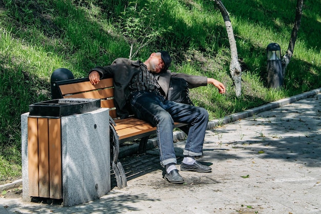 The man is tired and lies in the park on a bench