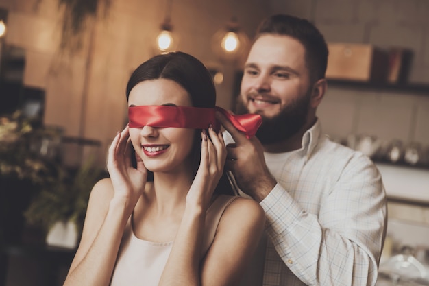 A man is tying a beautiful girl with a red ribbon