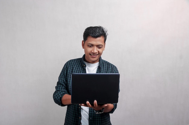 A man is using a laptop and smiling