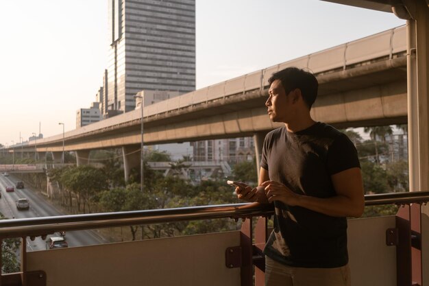 Man is using mobile phone while walking on the city bridge