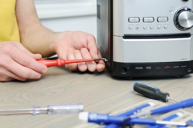 The man is using a screwdriver to open the music system.