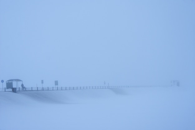 男は霧の中で雪に覆われた道で輸送を待っています