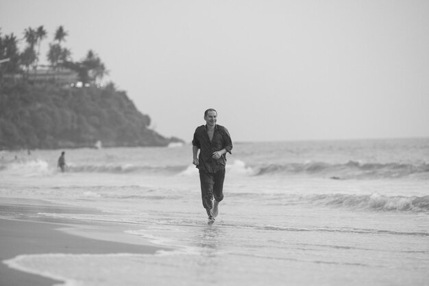 A man is walking on the beach in black and white