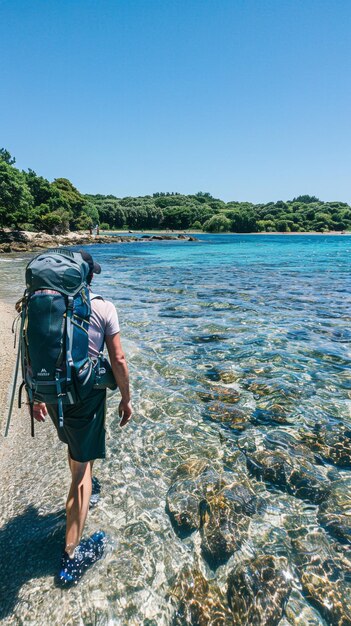 Foto un uomo sta camminando su una spiaggia con uno zaino