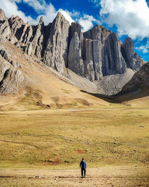 A man is walking in a field with a mountain in the background