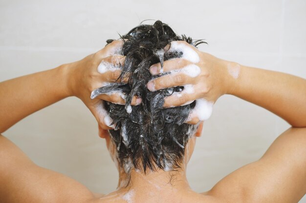 Foto un uomo si lava i capelli con lo shampoo