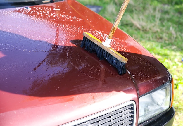 Photo man is washing old car. cleaning of vehicle outdoors. wet mop.