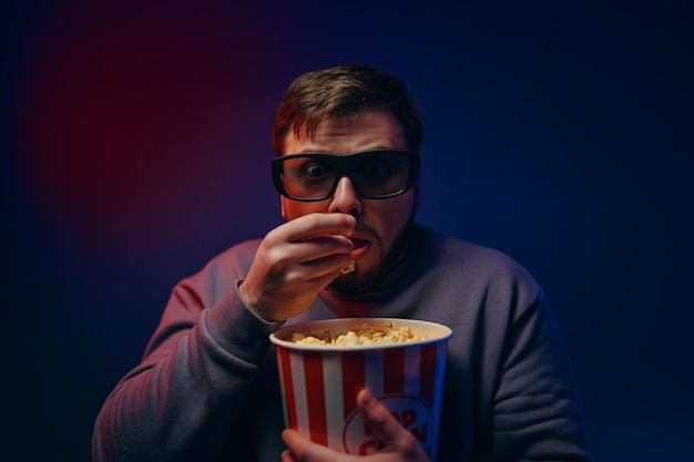 A man is watching a scary movie watching a movie with popcorn high quality photo