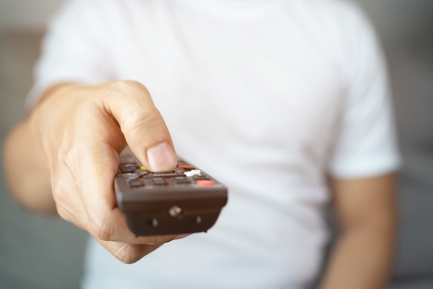 Photo man is watching tv with remote control in hand.