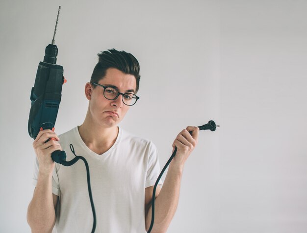 Man is wearing glasses does not know how to use a drill