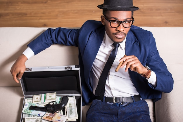 Man is wearing suit and hat with gun and money.