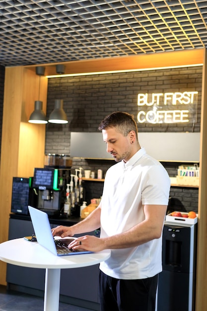 한 남자가 사무실 카페 지점에서 노트북으로 일하고 있다