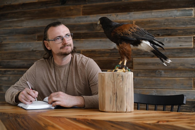 男は野生のワシの鳥と一緒に書いています