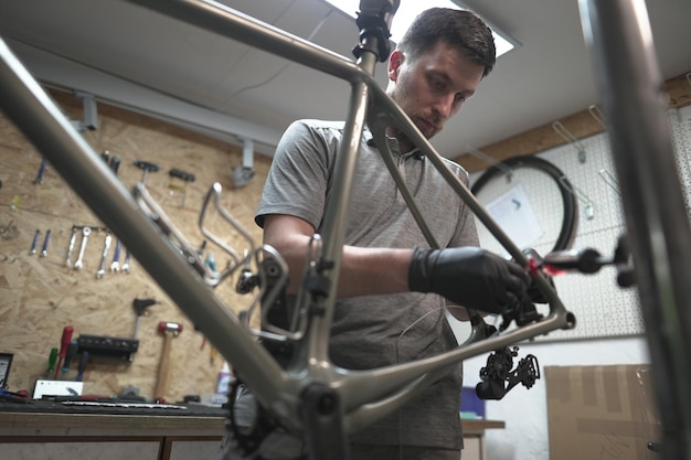 自転車のフレームに焦点を当てているワークショップの男性近くには自動車タイヤ自転車部品があります