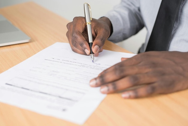 a man is writing on a piece of paper with a pen