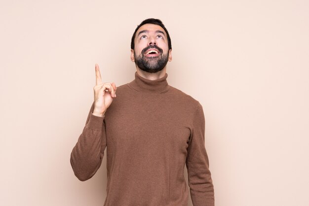 Man over isolated background pointing up and surprised