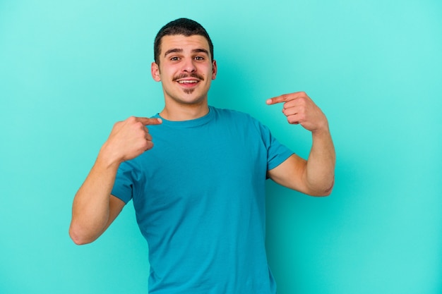 man isolated on blue surprised pointing with finger