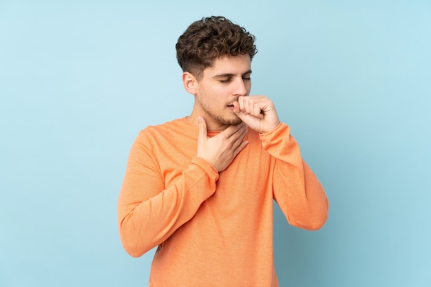 Man isolated on blue wall is suffering with cough and feeling bad