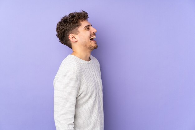 Photo man isolated on purple wall laughing in lateral position