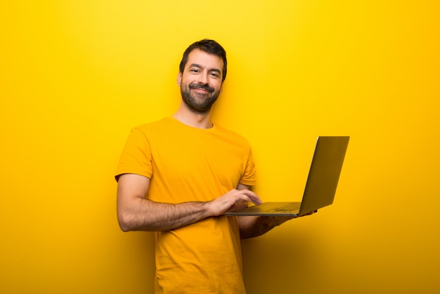 Man on isolated vibrant yellow color with laptop