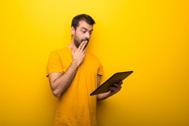 Man on isolated vibrant yellow color with a tablet