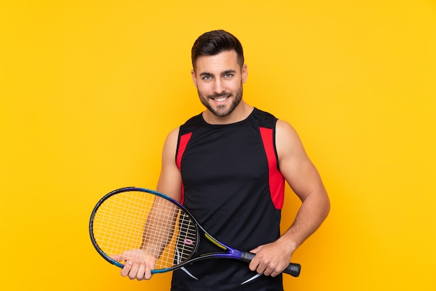 man over isolated yellow wall playing tennis