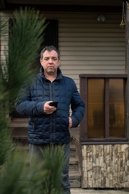 Foto un uomo con una giacca davanti alla sua casa di campagna