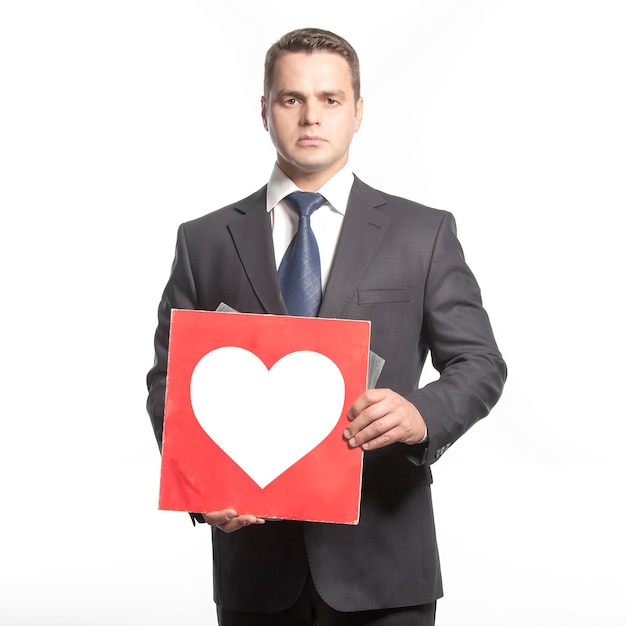 Man in a jacket holding in hands with red plate with the image white heart